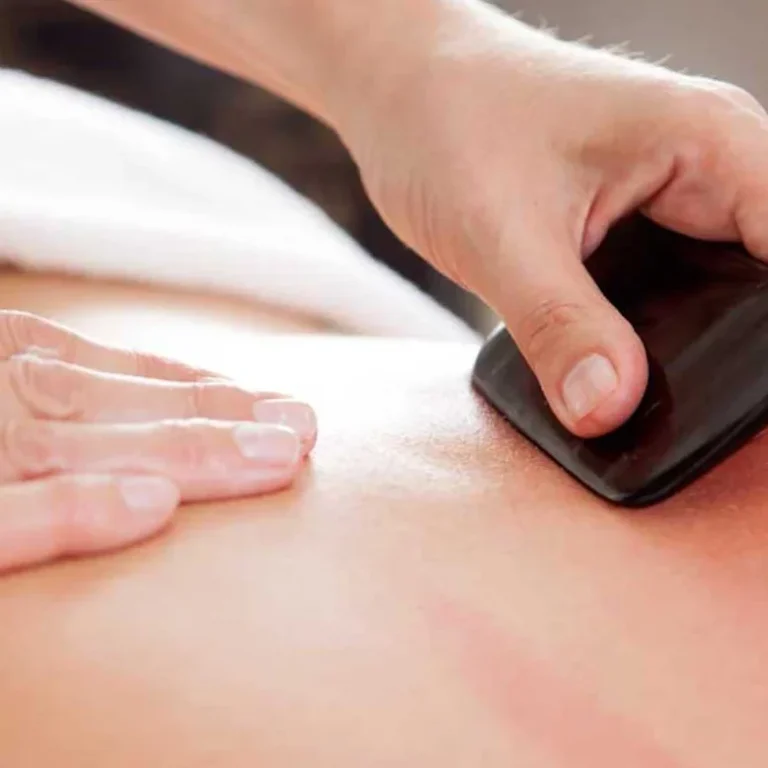 Eine Hand verwendet ein Massagegerät auf dem Rücken einer Person.